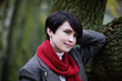 A woman leaning against a tree in autumn time