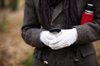 A woman holding a hot drink and flask outside in autumn