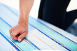 Cropped view of a surfer scraping the wax from his board with a