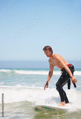 Photo: A young male surfer standing on his surfboard A young male surfer standing on his surfboard