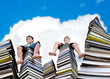 Little boys sitting on large stack of books