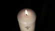 Candle with cross embellishment burning and being blown out