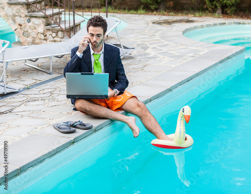Photo: Funny Young Businessman with SwimmingTrunks next to the Pool Funny Young Businessman with SwimmingTrunks next to the Pool