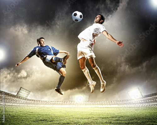 Photo: two football players striking the ball two football players striking the ball