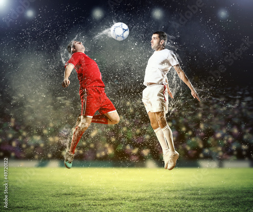 Photo: two football players striking the ball two football players striking the ball