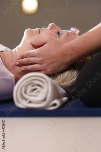 Photo: Young therapist arranging crystals on female client for reiki th Young therapist arranging crystals on female client for reiki th
