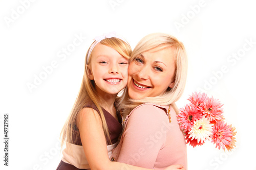 Photo: Happy mother and daughter hugging with flowers isolated on white Happy mother and daughter hugging with flowers isolated on white