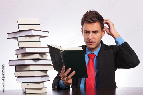 Photo: confused man reading at desk confused man reading at desk
