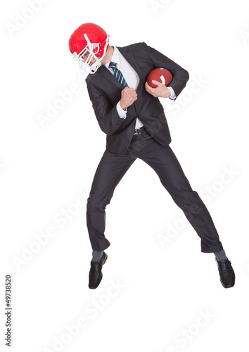 Photo: Competitive businessman playing american football Competitive businessman playing american football