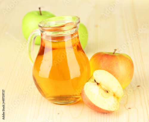 Photo: Full jug of apple juice and apple on wooden background Full jug of apple juice and apple on wooden background