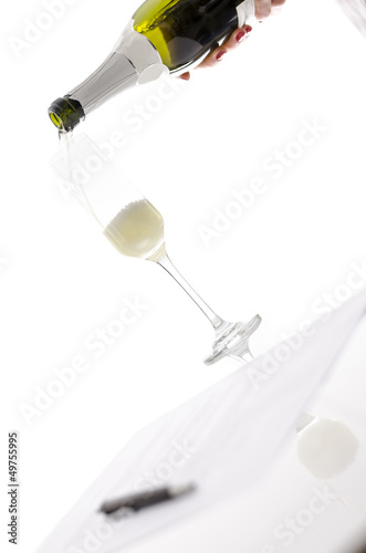 Photo: Woman pouring champagne into a glass over a contract Woman pouring champagne into a glass over a contract