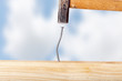 Crooked nail in the wooden board with a hammer