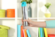 Sprayed air freshener in hand on white shelves background