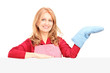 Smiling woman in apron posing with a cooking mitten behind a pan