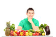 Young man posing with a pile of fruits and vegetables