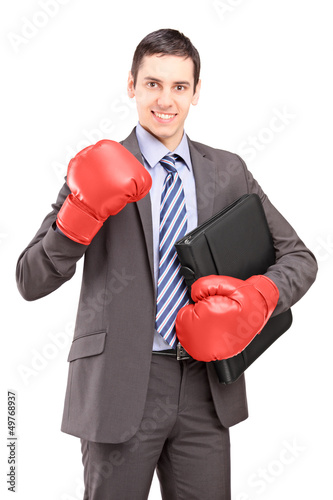 Photo: Young businessman with red boxing gloves holding a briefcase Young businessman with red boxing gloves holding a briefcase