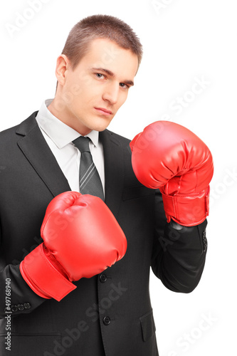 Photo: Young man in suit with red boxing gloves ready to fight Young man in suit with red boxing gloves ready to fight