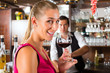 Woman holding a glass of wine in hand at the bar