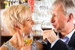 Senior couple at bar with glass of wine in hand