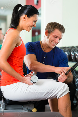 Photo: woman and Personal Trainer in gym, with dumbbells woman and Personal Trainer in gym, with dumbbells