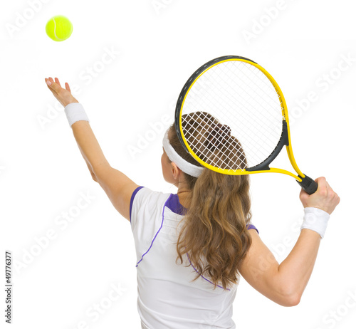 Photo: Tennis player serving ball. rear view Tennis player serving ball. rear view