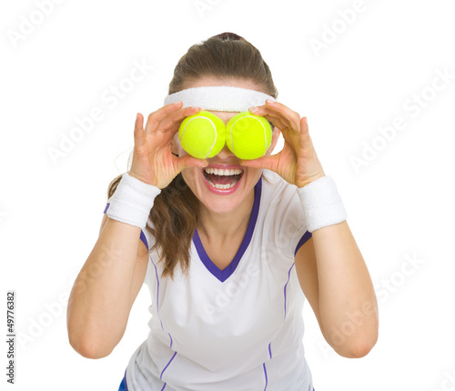 Photo: Happy tennis player holding balls in front of eyes Happy tennis player holding balls in front of eyes