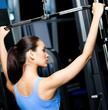 Athletic young woman works out on simulator in gym