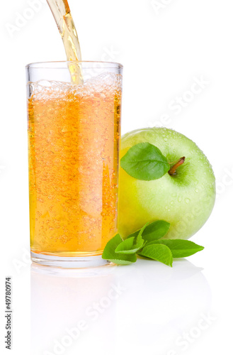 Photo: Pouring apple juice into a glass, green juicy apples with green Pouring apple juice into a glass, green juicy apples with green