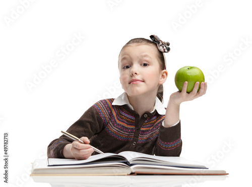 Photo: Schoolgirl with a green apple does her homework Schoolgirl with a green apple does her homework