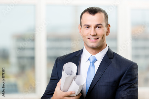 Photo: Contractor wearing suit with blue tie hands blueprints Contractor wearing suit with blue tie hands blueprints