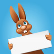 Osterhase zeigt Schild vor blauem Hintergrund