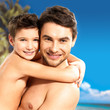  happy smiling father hugs son at tropical beach