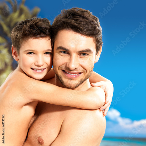 Photo: happy smiling father hugs son at tropical beach happy smiling father hugs son at tropical beach