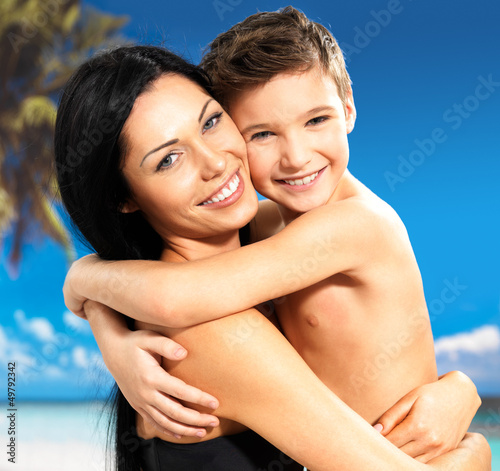 Photo: happy smiling mother hugs son at tropical beach happy smiling mother hugs son at tropical beach
