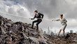 Two businessmen pulling rope atop of mountain