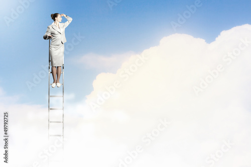Photo: Businesswoman standing on ladder Businesswoman standing on ladder