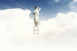 Businesswoman standing on ladder