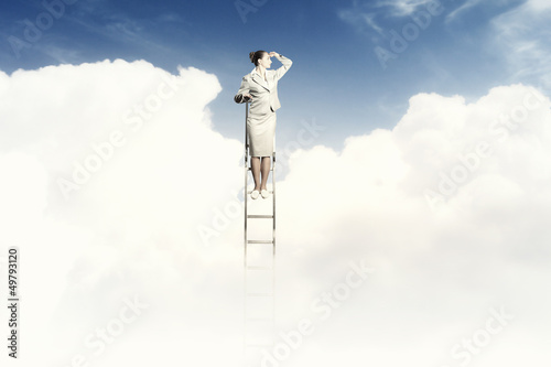 Photo: Businesswoman standing on ladder Businesswoman standing on ladder