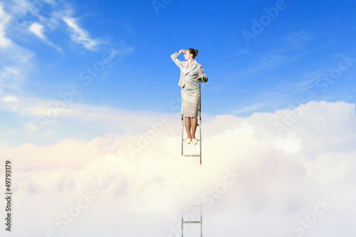 Photo: Businesswoman standing on ladder Businesswoman standing on ladder