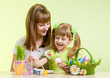 mother and child girl paint easter eggs over green