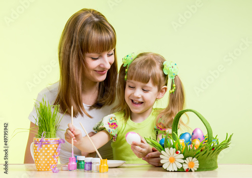 Photo: mother and child girl paint easter eggs over green mother and child girl paint easter eggs over green