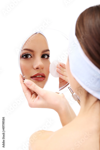 Photo: Young woman cleansing her face, isolated on white Young woman cleansing her face, isolated on white