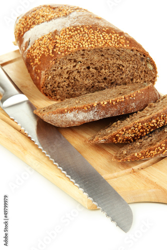 Photo: Bread with sesame seeds and knife on wooden board close up Bread with sesame seeds and knife on wooden board close up