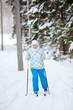 Happy Caucasian woman skiing in wintry forest alone