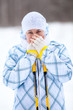 Attractive woman warming frozen hands with ski poles in winter