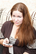 Photo: Portrait of unhappy young woman with cellphone in domestic room Portrait of unhappy young woman with cellphone in domestic room