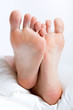 Woman's feet in bed on a Sunday morning