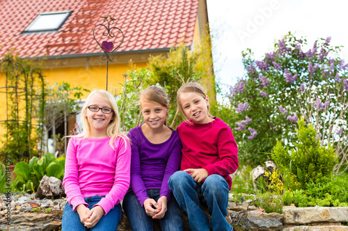Photo: Laughing kids sit in front of the house in the garden Laughing kids sit in front of the house in the garden