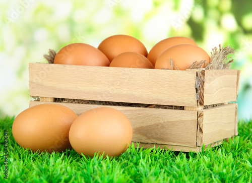 Photo: Many eggs in box on grass on bright background Many eggs in box on grass on bright background