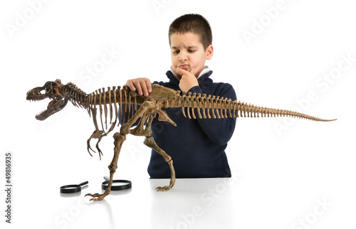 Photo: Little child thinking about dinosaur skeleton isolated on white Little child thinking about dinosaur skeleton isolated on white